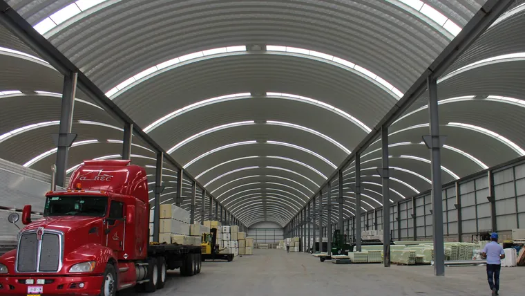 Almacén de panel aislante en el Estado de México: estibas de multipanel a ambos lados del pasillo y una plataforma cargando